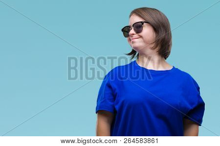 Young adult woman with down syndrome wearing sunglasses over isolated background looking away to side with smile on face, natural expression. Laughing confident.