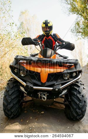 Rider in helmet on quad bike, front view, closeup