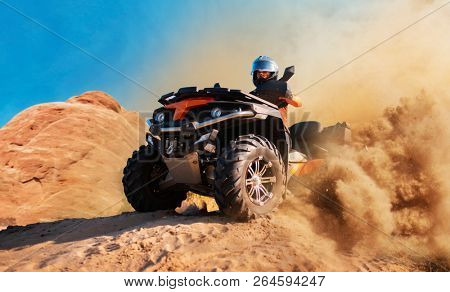 Quad bike in dust cloud, sand quarry on background