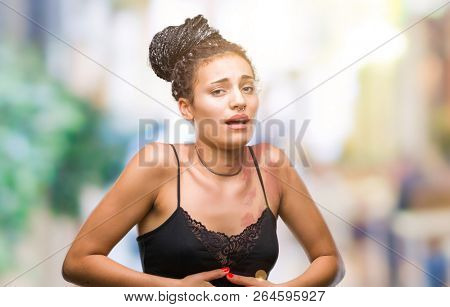 Young braided hair african american with pigmentation blemish birth mark over isolated background with hand on stomach because indigestion, painful illness feeling unwell. Ache concept.