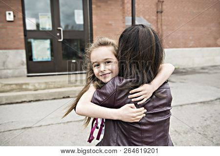 A Girl Child And His Mother Hugging Outside At School