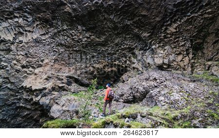 Man Standing In Front Of Basalt Columns Wall In Gjain Canyon, Iceland.