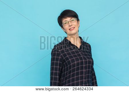 Middle Aged Woman With Pixie Haircut On Blue Background With Copy Space