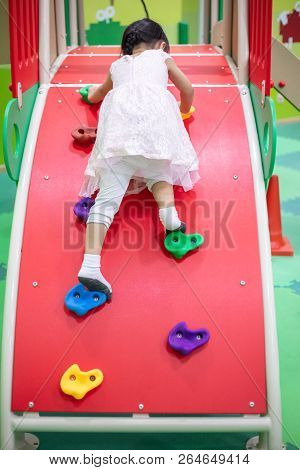 Asian Chinese Little Girl Playing At Mini Rock Climbing Wall At Indoor Playground