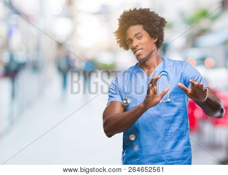 Afro american surgeon doctor man over isolated background disgusted expression, displeased and fearful doing disgust face because aversion reaction. With hands raised. Annoying concept.