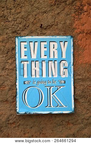 Positive Quote Of Everything Is Going To Be Ok On The Blue Plate Hanging On The Rough Brown Wall