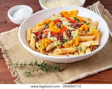 Penne Pasta With Yellow Tomatoes, Red And Green Vegetables, Mincemeat On Dark Wooden Background, Sid