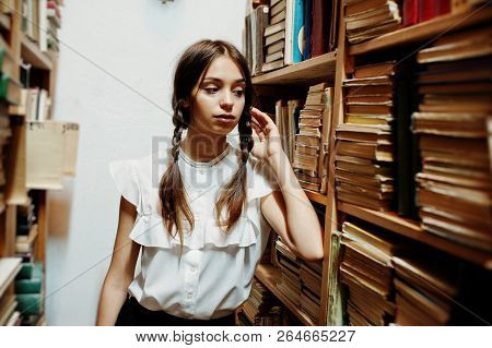 Girl With Pigtails In White Blouse At Old Library.