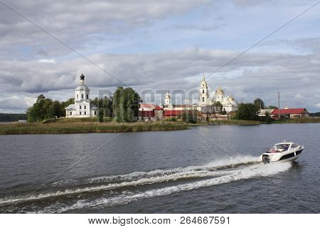 Motor Boat Sailing Past The Chirch Along The River, Nilov Monastery Seen From Water In Russia, Selig