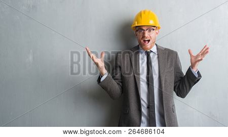 Young redhead man wearing architect outfit and helment very happy and excited, winner expression celebrating victory screaming with big smile and raised hands