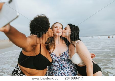 Beautiful curvy women taking a selfie at the beach
