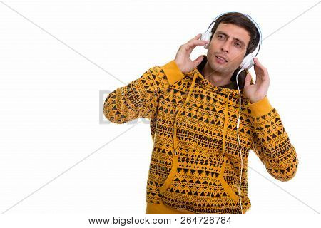 Studio Shot Of Young Handsome Man Listening To Music While Holdi