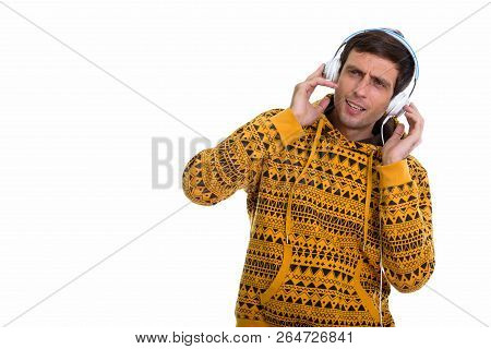 Studio Shot Of Young Handsome Man Listening To Music While Holdi