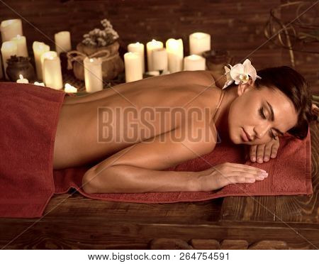 Chiropractic ayurveda massage therapy of woman in spa salon. Girl on candles background in massage spa salon. Luxary interior in oriental therapy salon. Brown sepia on dark .