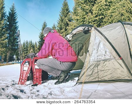 Hiker Prepare Equipment For Snowshoes Trip. Winter Few Days Trek In Snowy Mountains. Light Green Ten