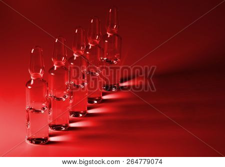 Row Of Ampulas With Medicine On Red Background