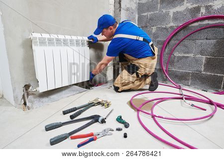 plumber at work. Installing water heating radiator