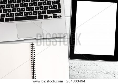 Directly Above Shot Of Laptop, Tablet Computer And Spiral Notepad On Rustic White Wooden Table