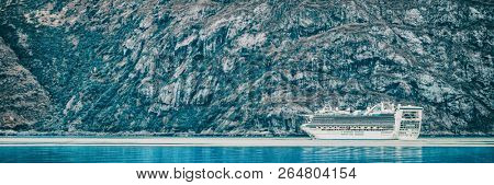 Cruise ship sailing at Glacier Bay, Alaska, on blue glacial ocean water and icebergs. Panoramic banner of Arctic travel background. Luxury vacation.