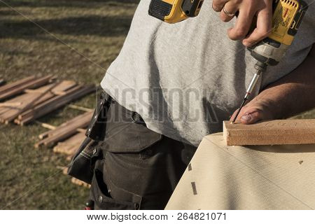 Roof Construction Building. Man Using Electrical Scredriver To Attach Construction Elements.