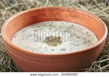 Beautiful Serving Vintage Ceramic Bowl of Homemade Kefir Soup Dovga or Tarator. National Sour-Milk Meal of Azerbaijani Cuisine with Yogurt, Herbs and Greens on Rustic Background Close Up