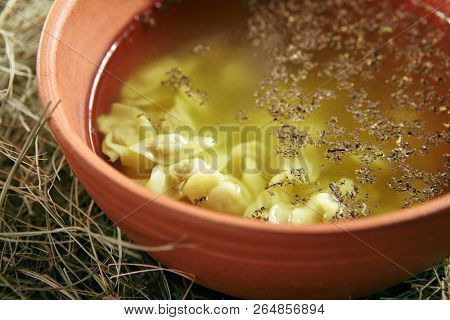Beautiful Serving Vintage Ceramic Bowl of Homemade Soup with Mini Dumplings on Rustic Background