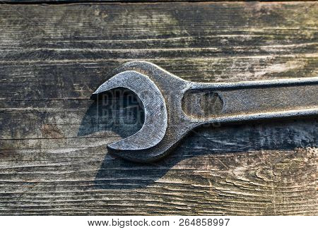Old Black Metal Key Close-up On The Background Of A Wooden Table. Construction Tool. Plumber