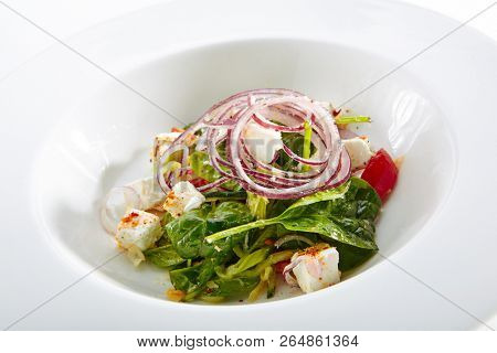 Green Salad with Goat Cheese, Spinach, Tomato and Red Onion Rings Isolated on White Background. Restaurant Starter Menu with fresh Spinacia and Chard Leaves, Tomatoes, Greens, Spices Close Up