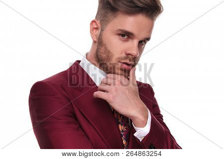 portrait of seductive man in grena suit thinking while standing on white background