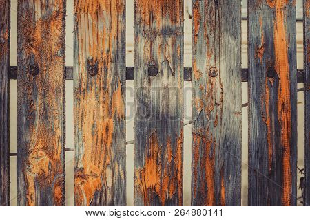 Old Fence With The Orange Peeled-off Paint And Nails