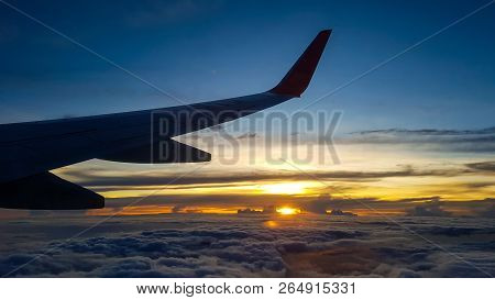 Silhouette Of Jet Plane's Wing Over The Clouds At High Altitude When Sunset.
