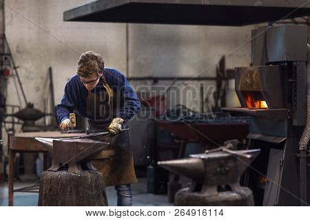 Young Blaksmith Working With Hot Metal In A Workshop