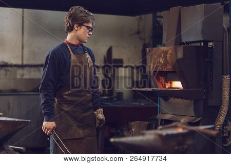 Young Metalworker Watching A Burning Furnace