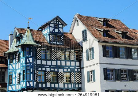 Travel To Switzerland. Wooden House With An Unusual Painted Facade And Red Tile Roof