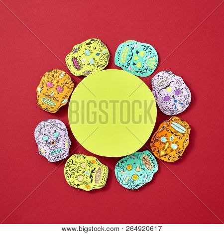 Handcraft paper Calaveras attributes of the Mexican holiday Calaca are decorated with a round yellow frame on a red background with space for text. Flat lay