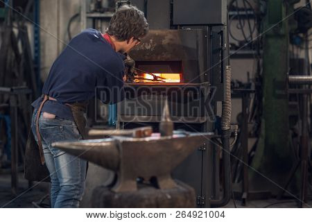 Young Blaksmith Working In A Metalworking Workshop