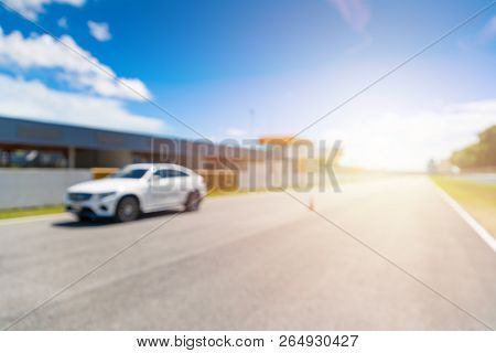 Abstract Blur And Bokeh. White Luxury Car In Racetrack And Speed Racing Back Ground Clear Sky. Sunli