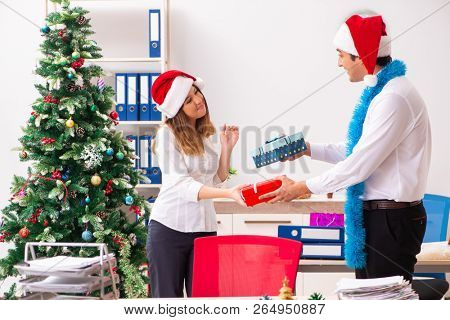 Colleagues exchaing christmas presents in office