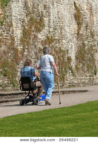 Zakázán dvě fenky, jeden sedí na elektrické mobility skútr a ostatní jít vedle wi