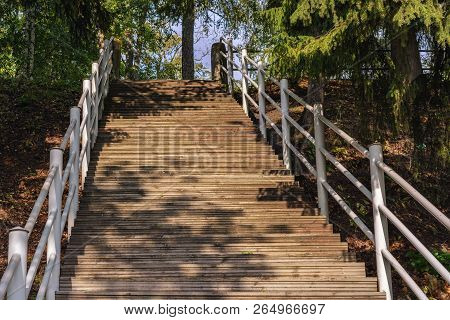 Staircase With Wooden Steps And White Metal Railings Leading To The Top.