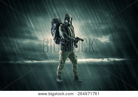 Terrorist in a stormy space with gas mask on his hand and weapons on his arm