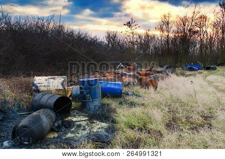 Barrels Of Toxic Waste In Nature With Dramatic Sunsets. Environmental Pollution.