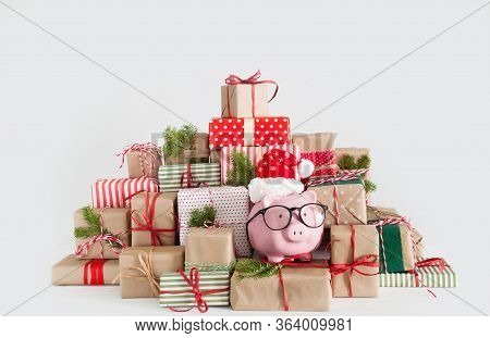 Piggy Bank In Santa Claus Hat. Christmas Gift Boxes. White Background. The Concept Of Saving.