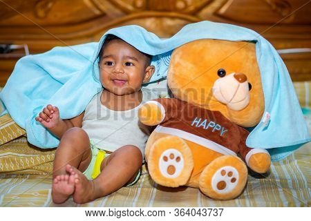 A Six Months Age Asian Baby Boy Playing A Yellow Taddy Bear.