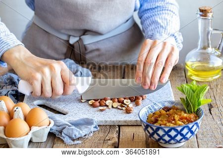 Grinds Hazelnuts. A Cook Grinds A Nut On A Board With A Knife. Hazelnuts On The Board. Stuffing With