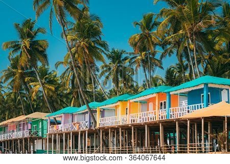 Canacona, Goa, India. Famous Painted Guest Houses On Palolem Beach Against Background Of Tall Palm T