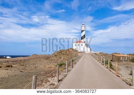 View Of The Lighthouse (faro De Favaritx) In Sunny Weather With Beautiful Clouds In The Sky On The I