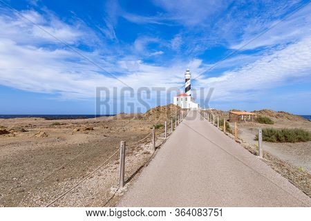View Of The Lighthouse (faro De Favaritx) In Sunny Weather With Beautiful Clouds In The Sky On The I