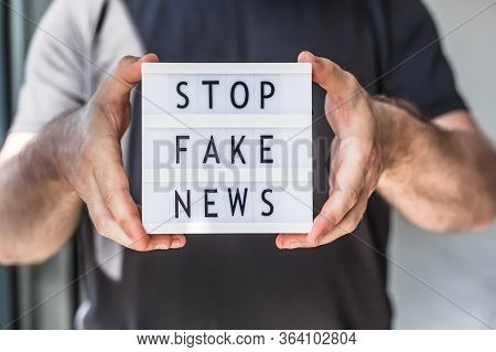 Fake News Infodemics During Covid-19 Pandemic Concept. Man Hands Holding Lightbox With Text Stop Fak