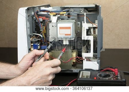 Repair Of A Microwave Oven, Repair Of Household Appliances. The Master Measures The Voltage With A T